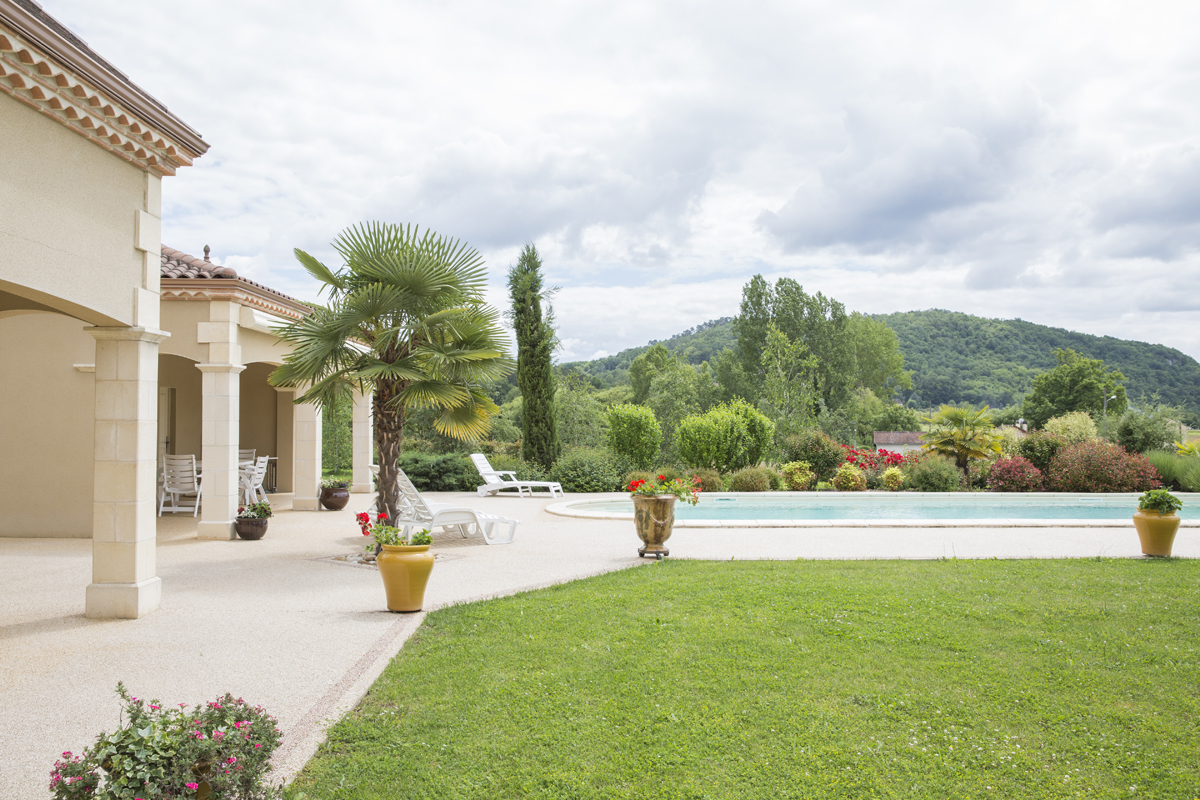 Réalisation d'une maison Aura de type périgourdine vue d’extérieure montrant la vue via le jardin.