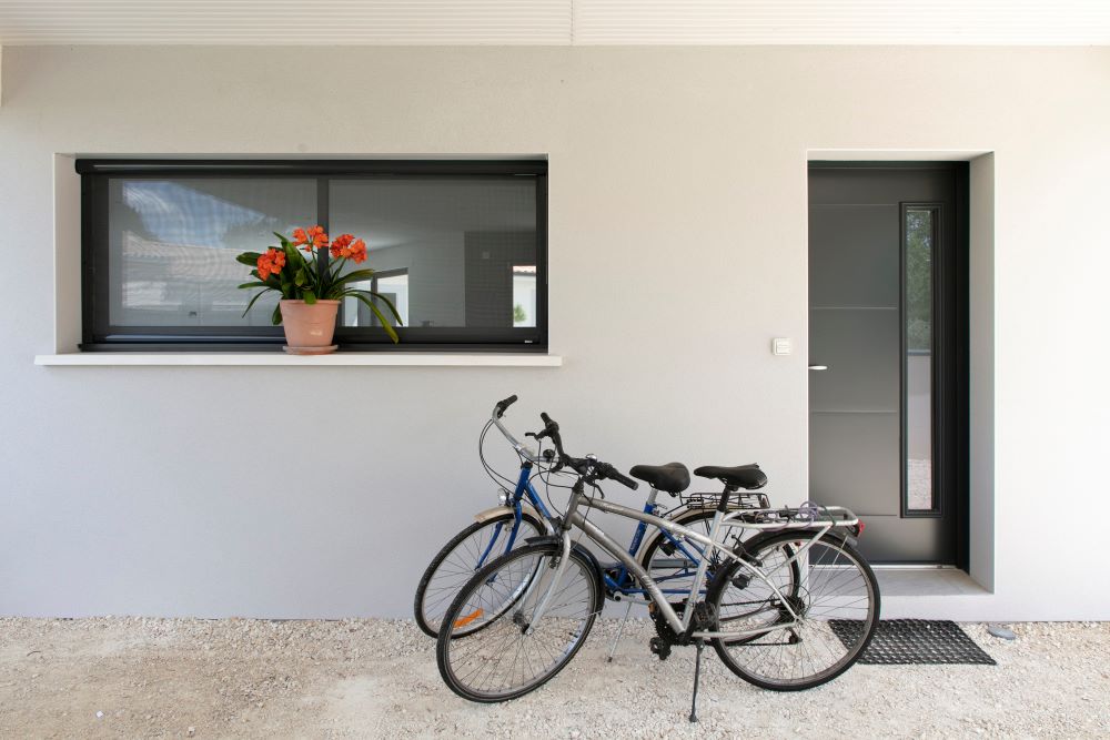Entrée moderne d'une maison avec fenêtre horizontale et vélos devant la porte
