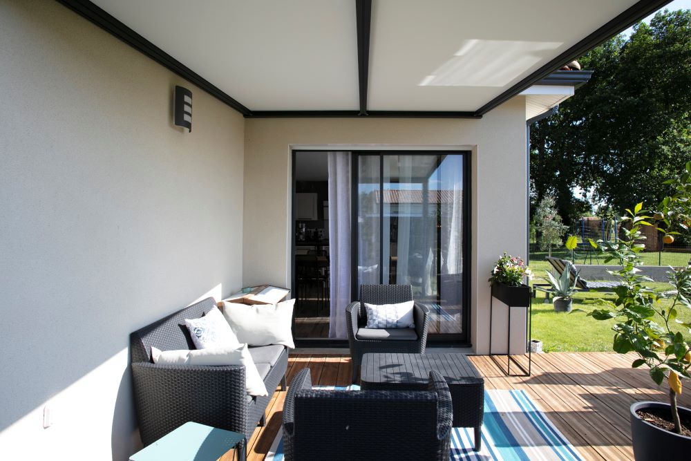 Terrasse couverte en bois avec salon de jardin et baie vitrée