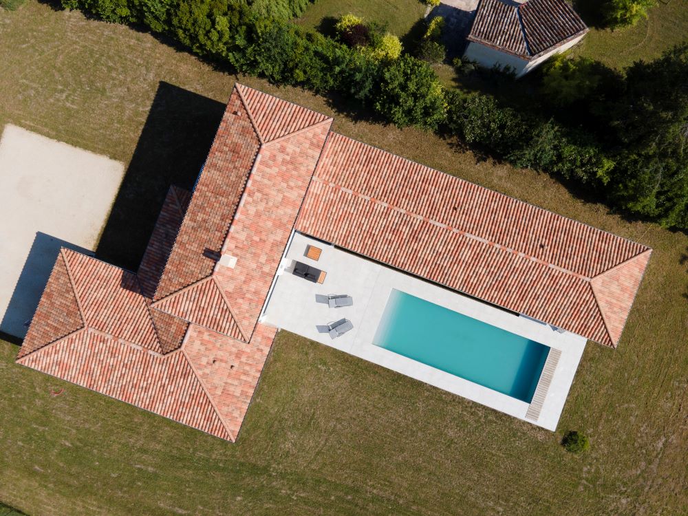 Vue drône d'une maison à l'architecture destructurée avec piscine