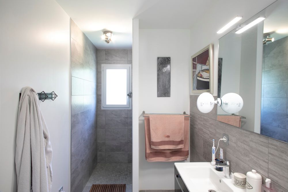Salle de bain moderne avec grand miroir et douche à l'italienne